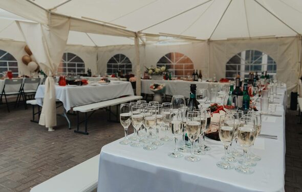Усадьба Афонинская. Большой шатер с белым потолком и стенами, прозрачные окна полукруглой формы. Длинные столы, покрытые белыми скатертями, сервировка бокалами и бутылками. Ряды складных стульев и лавки. Пол из серых плиток. Декор из цветов и воздушных шаров.