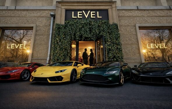Level 5(Лэвел 5). Фасад здания с большими окнами, текст "LEVEL" над входом и на оконных витринах, стены из текстурного камня, зелёные растения обрамляют вход. Перед входом припаркованы спортивные автомобили красного, жёлтого, зелёного и чёрного цветов.