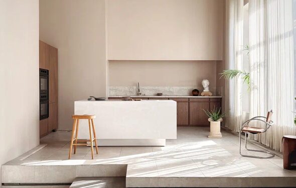 Киото. Светлый зал с кухней. Кухонное пространство с островом и барным стулом, деревянные шкафы, встроенная техника, мраморная столешница, светло-бежевые стены, большое окно с легкими шторами, стеклянный стул, растения в горшках, светлое плиточное покрытие.