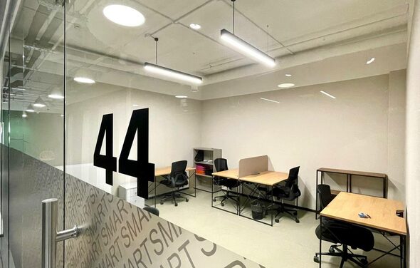 Smart Coworking(Умный Коворкинг). Офисное помещение с четырьмя рабочими местами, разделёнными столами и стульями на колёсиках. Стеклянная дверь с надписью «44». Освещение из подвесных светильников. Светлые стены и пол. Открытые потолочные коммуникации.