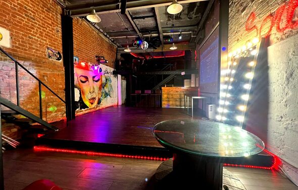 Soul Loft . Крупный план угла большого зеркала и гирлянд на ней, всё расположено у кирпичной стены