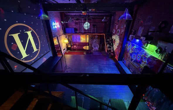 Лофт ИЗНАНКА. Зал ЛИХИЕ 90-е. Затемнённая комната лофта, много людей в кадре проводят фуршетное мероприятие, беря еду с объединённых столов. Несколько людей на кадре танцуют