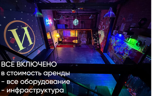 Лофт ИЗНАНКА. Зал ЛИХИЕ 90-е. Затемнённая комната лофта, много людей в кадре проводят фуршетное мероприятие, беря еду с объединённых столов. Несколько людей на кадре танцуют