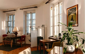 Светлый лофт с панорамным видом. Большие окна. Столы с лампой и цветком, стулья