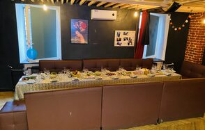 Караоке-бар в центре города. Диваны с небольшими квадратными столами. Телевизор. Гирлянда