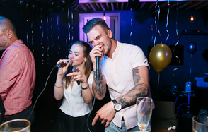 Караоке-бар в центре города. Барная стойка с барными стульями. Большие колонки. Телевизор. Чёрная кирпичная стена с нарисованной Джессикой Рэббит