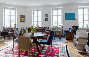 Светлый лофт с панорамным видом. Столы со стульями. Ковры на полу. Различные элементы декора