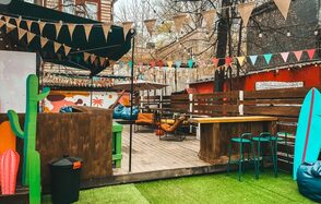 Лофт Surf (Серф). Тропический лофт с большой верандой.. Деревянная терраса с деревянными барными стойками и стульями, палатка с флажками, разноцветные флажки и гирлянды из лампочек, искусственная трава, деревянные заборы, мягкие кресла и пуфы, декоративные кактусы, доска для серфинга, яркие стены.