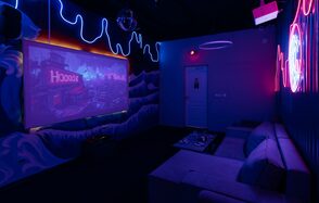 Rubin Loft (Рубин Лофт). Зал Токио. Караоке-комната с темным интерьером, неоновое освещение и светодиодная лента на стенах, проекционный экран с изображением, два серых дивана, журнальный столик с пультом, диско-шар на потолке, светящиеся надписи на стене, проектор крепится на потолке.