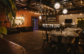 Nord Loft(Норд Лофт). Лофт-пространство с кирпичными стенами, круглым столом, черными стульями, кожаными диванами. Барная стойка с подсветкой, декор бутылками. Потолочные светильники в виде звезд. Стена с зеленью, светодиодные гирлянды, элементы неоновой вывески.