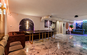 Стильный лофт Джаванди. Современное пространство с мраморным полом и светлыми стенами. Комплектация включает длинный стол с золотистыми ножками, диваны, стулья. Освещение разноцветное, неоновое, с декоративными панелями на стенах. Декор включает искусственные цветы и картины.