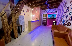 Яркий двухуровневый лофт. Барная стойка. Холодильник. Разноцветные украшенные стены. Диваны. Телевизор. Лестница на второй этаж