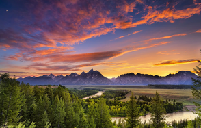 Тестовый зал мск. На картинке изображен живописный пейзаж: хвойный лес на переднем плане, извивающаяся река, горный хребет вдалеке. Небо окрашено в яркие цвета заката, создавая атмосферу спокойствия и красоты.