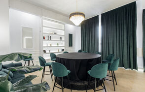 Rubin Loft (Рубин Лофт). Зал Империал. Просторная комната с круглым столом, покрытым черной скатертью, окруженным зелеными стульями. На стене белые полки с декором, в центре потолка большая люстра, длинные темные шторы, плиточный пол, комнатные растения.