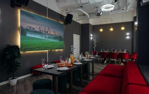 Rubin Loft (Рубин Лофт). Лофт Вегас. Зал с длинным черным столом и красными стульями, рядом висят круглые подвесные светильники. На стене большая панорама с подсветкой, изображающая город и поле. Потолок белый с видимыми коммуникациями. Напольное покрытие — темное.