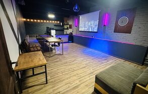 Kahovka loft (Каховка Лофт). Неоновый лофт-зал. Коворкинг-пространство с деревянным полом, кирпичными стенами серого цвета, длинным деревянным столом и креслами вдоль стены. Присутствует проектор, экран, атмосферное освещение, барная стойка и оригинальное настенное панно.