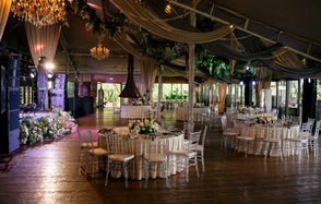 Soho Country Club (Сохо Кантри Клаб). Банкетный зал с деревянным полом и высоким потолком, декорирован тканями и зеленью. Круглые столы с бежевыми скатертями и прозрачными стульями. В центре люстры, сцена с музыкальной аппаратурой и цветами, витражные окна, освещение с оттенками розового и зелёного.