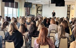 Зал 9. Просторный конференц-зал до 200 человек в Академии Кантаты. Конференц-зал с белыми стенами и окнами с защитными шторами. Размещение стульев в рядах; организатор на сцене с микрофоном. Потолочные динамики, светильники и подвесные экраны. Светлые стены, ковровое покрытие.