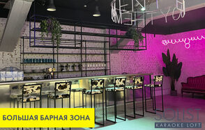 Солист лофт | Solist loft - яркая площадка на Лиговском. Барная зона с длинной барной стойкой и высоким стульями с черно-белыми сиденьями. Кирпичные стены, неоновая надпись, зелёные растения на каркасной полке. Розовая и фиолетовая подсветка, мягкий диван, бетонный пол, потолочные светильники. Текст: «Большая барная зона», «Solist Karaoke Loft».
