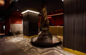 Микс Afterparty(После вечеринки). Коммерческое пространство с темными потолками, красными и бордовыми стенами. В центре статуя лошади на камне. Желтая барная стойка, мраморный пол со сложным узором. Диван в углу, приглушенное освещение, колонны с вертикальными линиями.