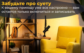 Лофт  Эйфория. Студия с жёлтым креслом, рядом круглый стол с чёрным микрофоном, книгой и стаканом. Слева стеллаж с книгами, растениями и декоративными элементами. Стена светлая, освещение тёплое. На стене текст: «Забудьте про суету...»