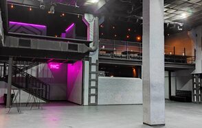 PRAVDA(Правда). Просторный зал на 800 гостей. Большое закрытое пространство с бетонным полом и высокими потолками, многоуровневое с лестницей, балкон. Есть знак "WC" с неоновой подсветкой, освещение в виде точечных светильников. Стены серые, чёрные деревянные и металлические элементы.