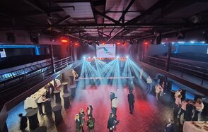 СВОБОДА. Зал на 1200 человек. Многоуровневое пространство для мероприятий с паркетным полом и металлическими перилами. Несколько столов с белыми скатертями и барными стульями. Яркое освещение с прожекторами, сцена с экраном. Люди в зале.