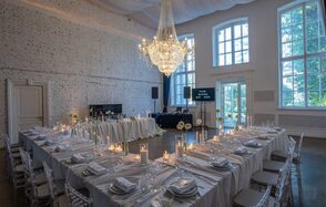 Лофт КОСМОС с летней верандой. Пространство для мероприятий с белыми кирпичными стенами, большим люстрой, светлыми скатертями, сервировкой столов, прозрачными стульями. Высокие окна, круглые и квадратные столы, свечи. Освещение теплое, дневной свет.