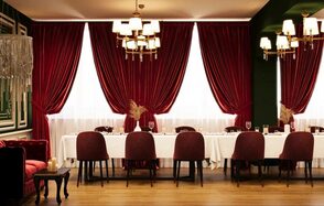 Вегас. Атмосферный лофт с акцентным дизайном. Банкетный зал с длинным столом, накрытым белой скатертью, окружённый бордовыми стульями. Красные бархатные шторы, зелёные стены, деревянный пол. Потолочные и настенные светильники с белыми абажурами. Декор из сухих растений, свеча на кофейном столике.