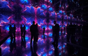 Futurione(Футурио́не). Интерактивное пространство с зеркальными стенами и полом, освещенное световыми проекциями космоса в ярких синих и фиолетовых тонах. Несколько человек стоят внутри, отражаясь в поверхностях.