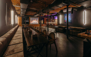 Авторские пространство T&S loft (ти энд си лофт) . Лофт-пространство с кирпичными стенами, металлическими балками и деревянным потолком. Длинные столы с мягкими стульями, кожаные диваны. Светильники на стенах, экран с изображением камина. Пол — тёмная плитка. Настенные живописные панно.