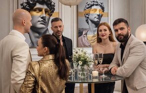 Level 5(Лэвел 5). Современное праздничное пространство с круглым стеклянным столом, за которым стоит группа людей. На стене два изображения классических скульптур с жёлтым акцентом. Стена белая с молдингами. Стол украшен цветами и бокалами шампанского.