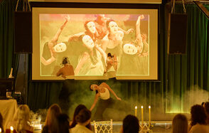 Arsenal Loft(Арсенал Лофт). Актовый зал с проектором, зелёные занавески, танцоры в масках, дымовая машина, зрители на стульях с золотыми спинками, свечи на столе.