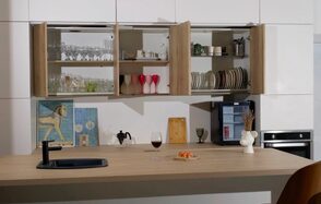 WhiteFox Studio(Студия Белая Лиса). Современная кухня с открытыми шкафами, наполненными посудой и бокалами. На столе бокал, тарелка с закуской, черный кран и раковина. Светлые стены, встроенная духовка, декоративные элементы и книги.