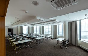 Конференц-зал Экспресс Махараджей. Просторное конференц-помещение с отдельными столами и черными стульями. Белые стены и потолок с встроенным освещением. Большие окна с жалюзи, панорамный вид. Ковровое покрытие коричневого цвета. Установлен кондиционер.