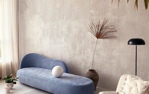 Киото. Светлый зал с кухней. Просторная комната с высокими потолками и светлыми стенами. Голубой диван округлой формы, рядом керамическая ваза с растением и лампа с черным абажуром. Светлые занавески пропускают естественный свет. Пол светлый, на нем стоит стол и растение.