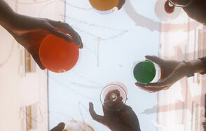 Винный бар “Дело не в вине”. Несколько рук держат цветные бокалы на фоне светлого неба.