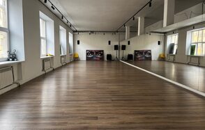 The Flow Space(Пространство Поток). Просторное помещение с деревянным полом, зеркалами вдоль одной стены. Белые стены, большие окна, обеспечивающие естественное освещение. Акустическая система и картины на задней стене. Потолочные светильники и несколько жёлтых стульев.