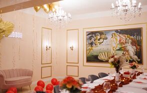 Барокко. Элегантный лофт. Праздничное пространство с длинным столом, покрытым белой скатертью и украшенным цветами. На стене объемная картина. Светильники на стенах и хрустальные люстры. Бежевые стены с золотыми элементами и неоновая вывеска. Красные и золотые шары на полу.
