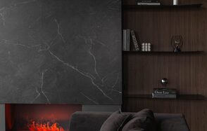 Зал Black. Фотостудия Мимика. Камин с имитацией огня, облицованный темным мрамором; рядом деревянные полки с книгами и декором; справа диван темного цвета. Освещение мягкое, создающее уютную атмосферу.