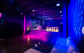 Стильный панорамный лофт на Петроградке. Улыбающийся мужчина, позирующий на камеру. На заднем плане дургие люди общаются