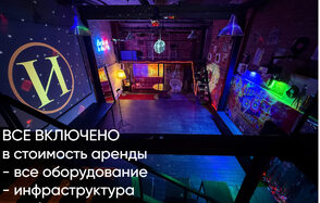 Лофт ИЗНАНКА. Зал ЛИХИЕ 90-е. Затемнённая комната лофта, много людей в кадре проводят фуршетное мероприятие, беря еду с объединённых столов. Несколько людей на кадре танцуют