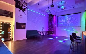 Barshowplace (БарШоуПлейс). Лофт для вечеринок с коктейльным баром . Просторное помещение с деревянным полом, белыми стенами и декоративной подсветкой. Натуральный и диско-шар освещение. Мебель: диван, барные стулья и стол. На стене большой экран с проектором. Декор: картина, неоновая надпись и зеркало с лампами.